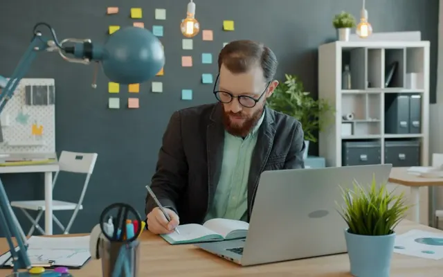 Person working with a laptop and notebook