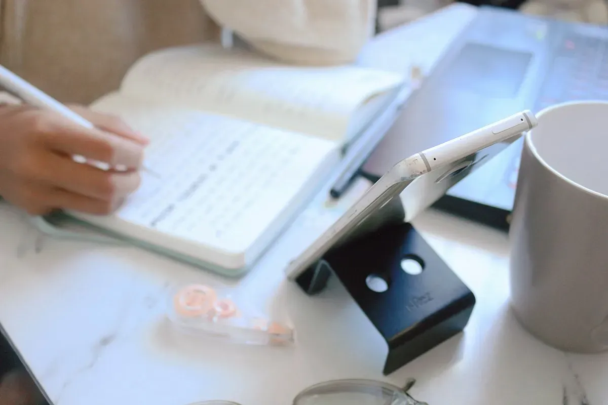 Hand writing notes beside a laptop