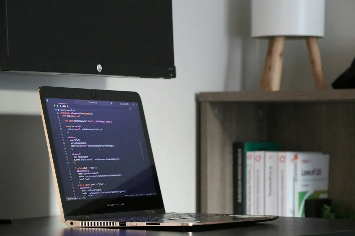 Laptop displaying code beside bookshelves