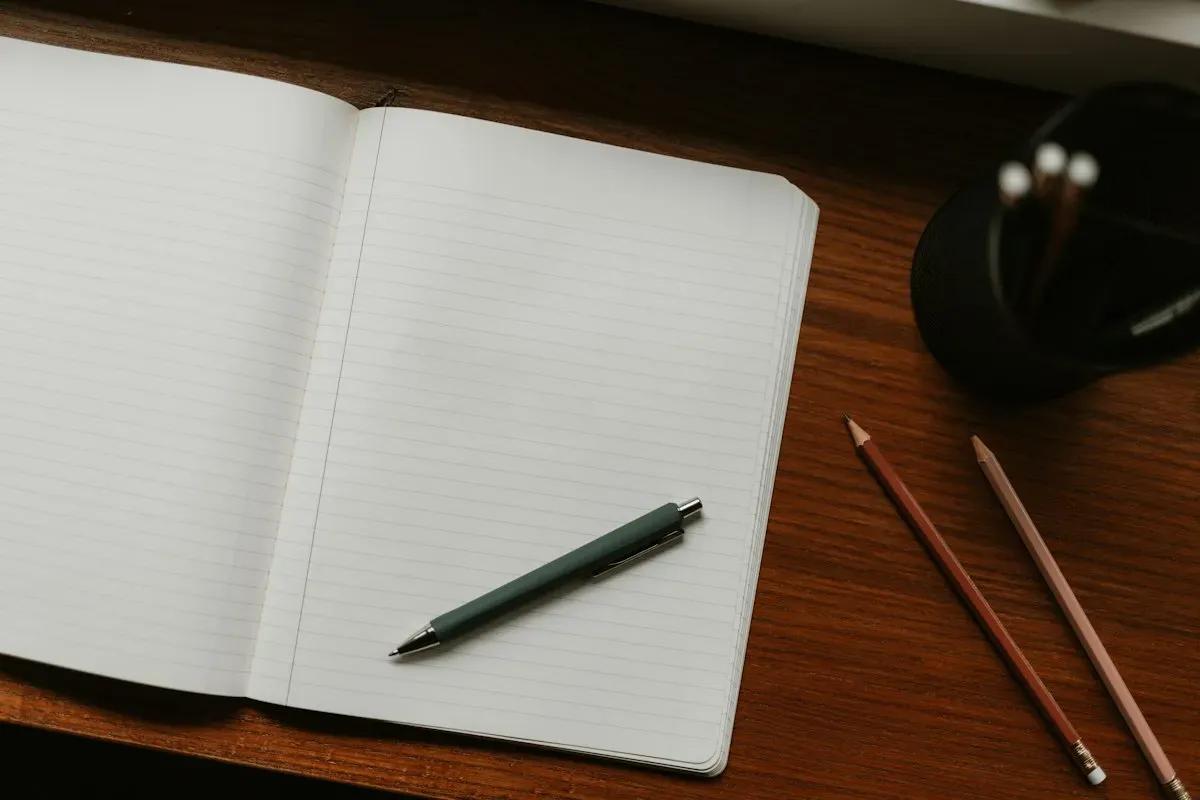 Open notebook with a pen and pencils